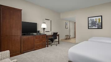 Habitación de hotel con una cama grande, un escritorio con silla, televisor, armario y un cuadro en la pared.