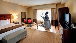 Une chambre d’hôtel équipée d’un lit, d’appareils de musculation, d’une télévision et d’un bureau.