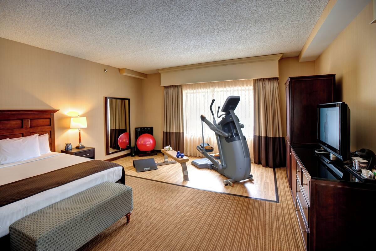Une chambre d’hôtel équipée d’un lit, d’appareils de musculation, d’une télévision et d’un bureau.