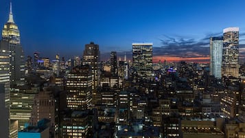 Un paisaje urbano al atardecer con rascacielos iluminados y un edificio destacado con aguja.