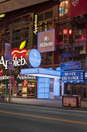 Un bâtiment sur lequel on peut voir des enseignes indiquant la présence d’un restaurant Applebee’s et d’un hôtel Hilton, ainsi qu’une enseigne pour un bureau de change.