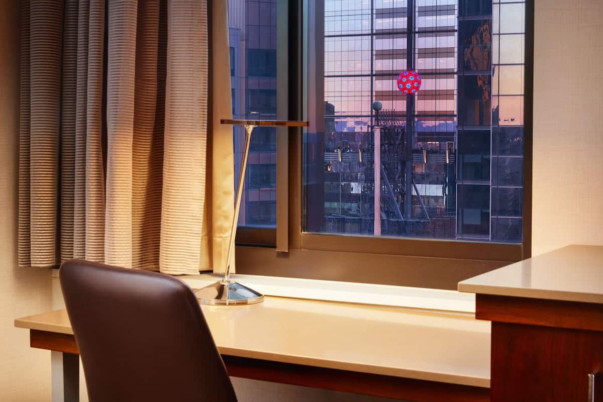 Un bureau avec une chaise, une fenêtre avec des stores et une vue sur le paysage urbain.
