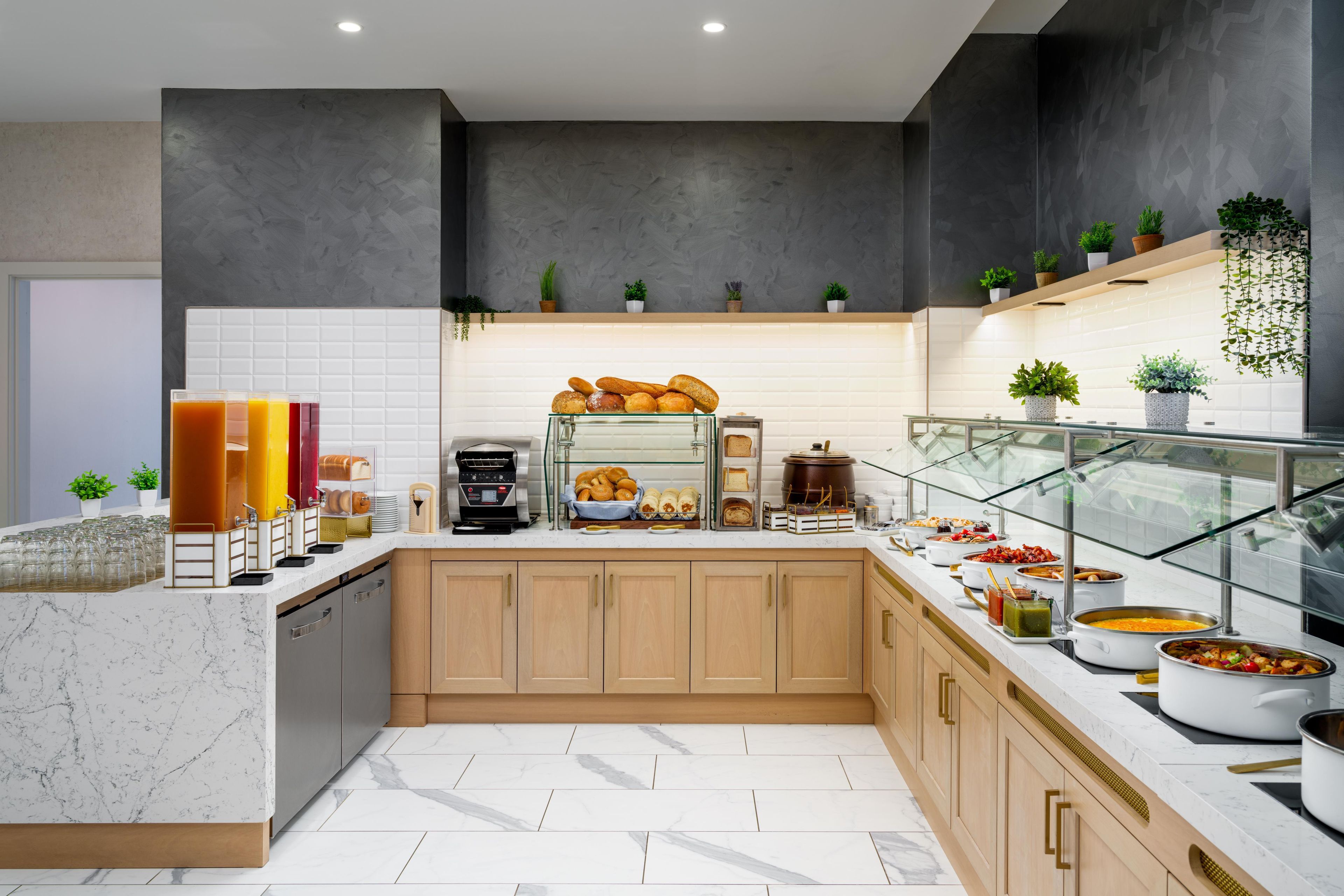 A modern kitchen with marble countertops, a coffee machine, and a variety of food items displayed on the counter.