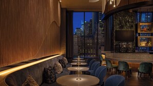 A modern bar area with seating and a city view. - Hilton New York Times Square (New York)