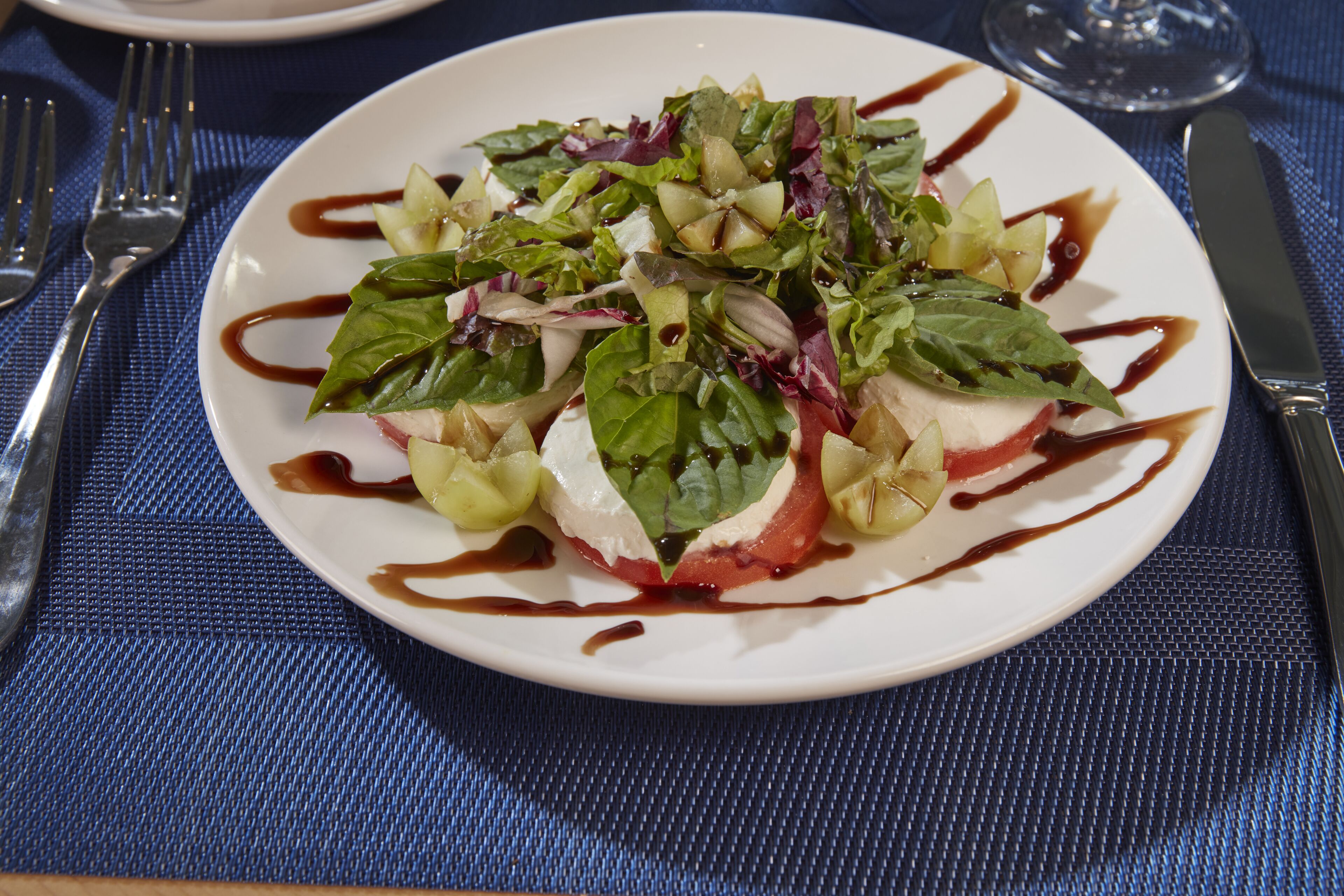 A white plate with a salad on a blue textured tablecloth.
