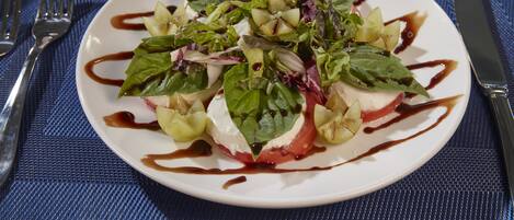 A white plate with a salad on a blue textured tablecloth.