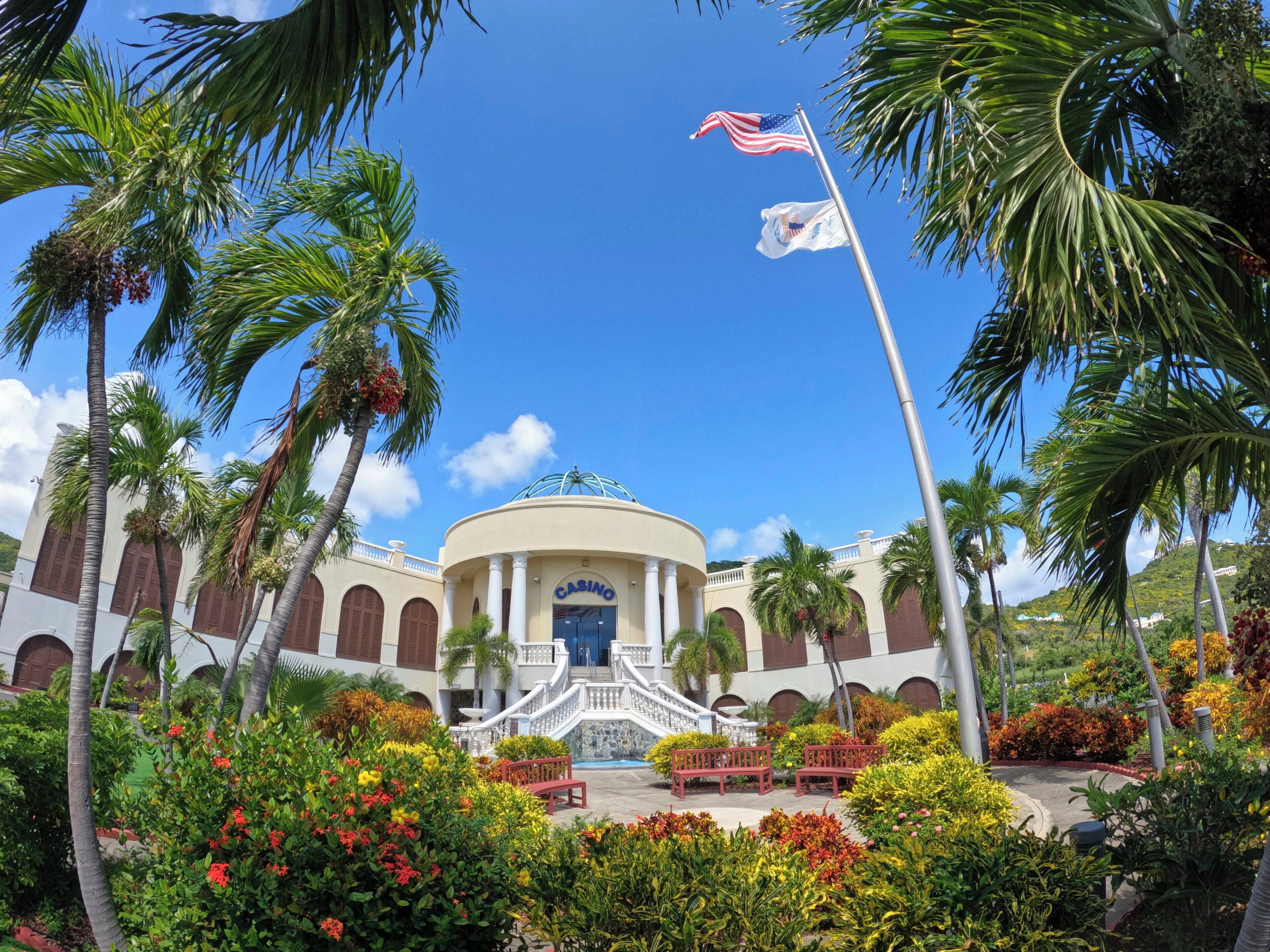 A building with a dome, arched windows, and a flagpole with two flags.
