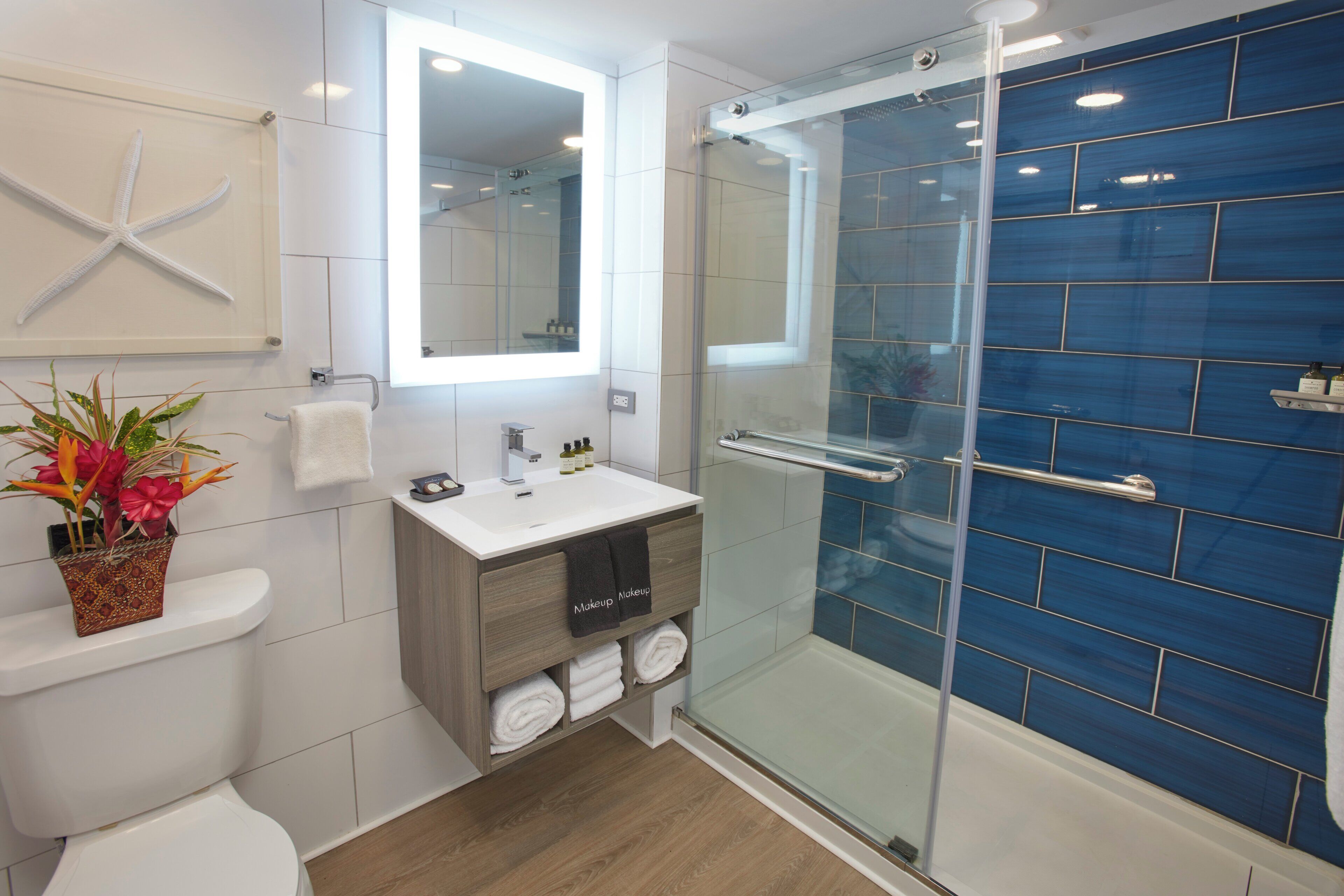 Un baño moderno con ducha acristalada, un lavabo blanco y una decoración con forma de estrella de mar en la pared.