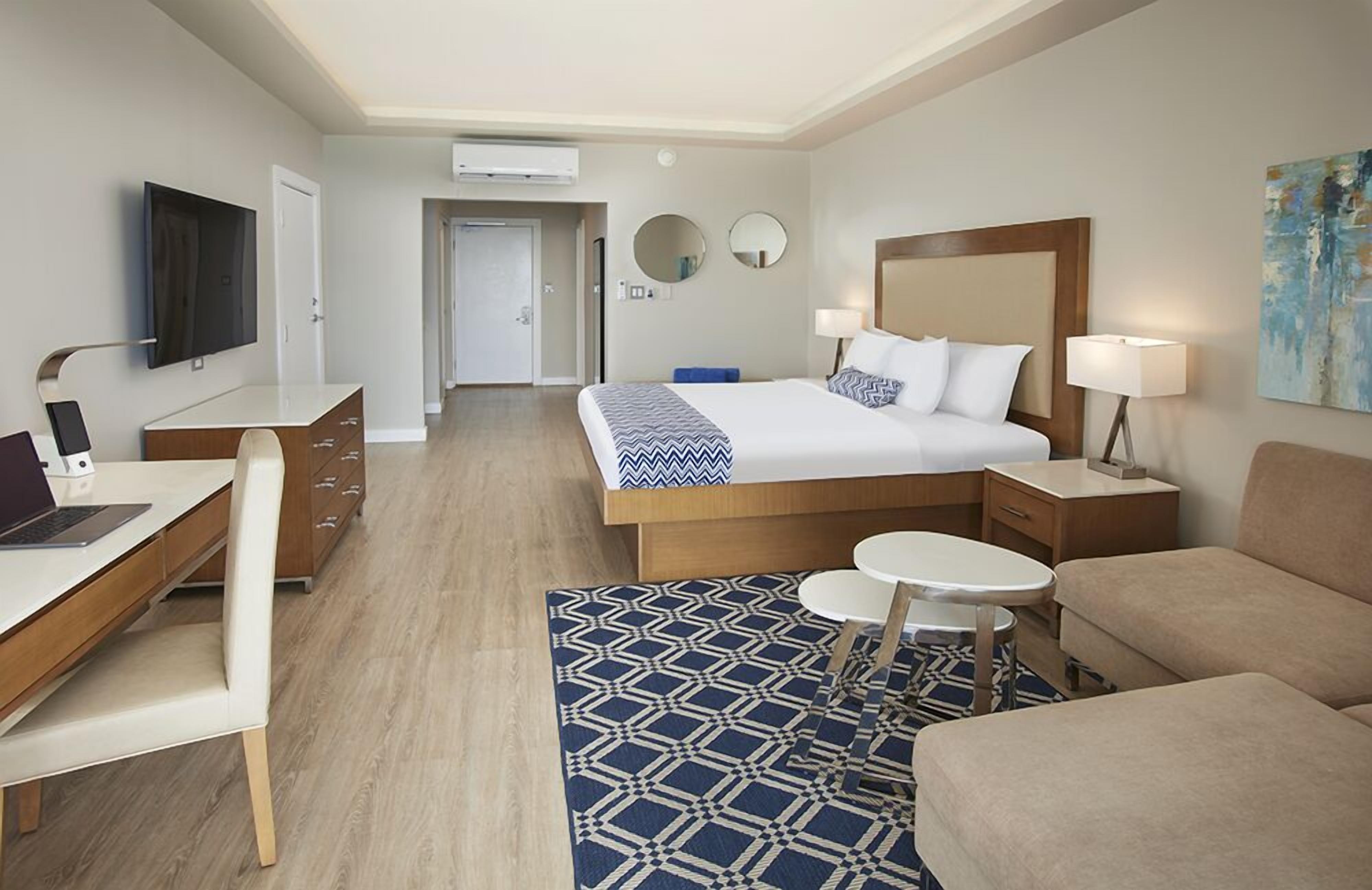 Ein Hotelzimmer mit Bett, Schreibtisch, Stuhl, einem kleinen Tisch und einer Couch.