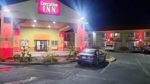 Hotel Executive Inn con aparcamiento y varios coches estacionados.