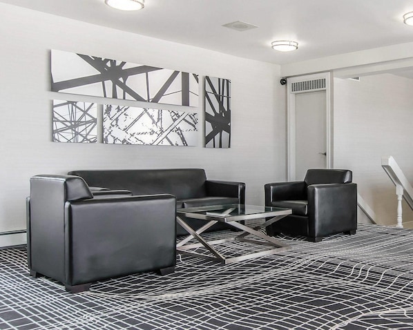A modern room with a black leather sofa, a glass coffee table, and abstract wall art. - Econo Lodge (Temiskaming Shores)