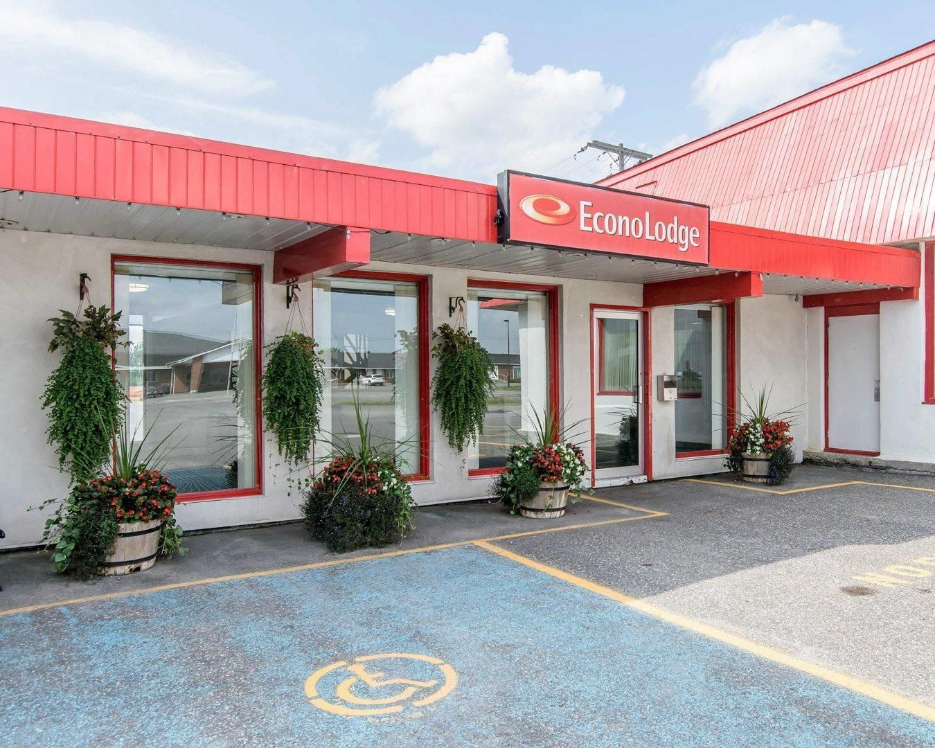 A building with a red roof and a sign reading 'EconoLodge.' There are potted plants in front of the entrance.