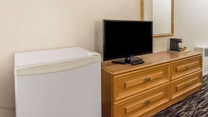 A hotel room with a white refrigerator, a wooden dresser with drawers, a flat-screen TV, a coffee maker, and a mirror on the wall. - Econo Lodge (Temiskaming Shores)