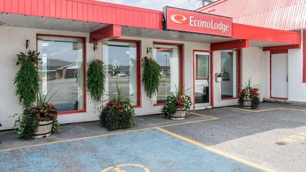 Ein Gebäude mit rotem Dach und einem Schild mit der Aufschrift "EconoLodge". Im Vorbereich befinden sich Blumentöpfe und ein Symbol für barrierefreien Zugang.