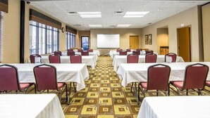 A conference room with multiple tables and chairs, a projector screen, and large windows. - Quality Inn & Suites Casper near Event Center (Casper)