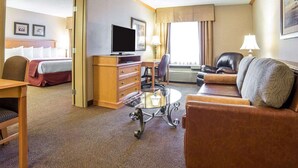 A hotel room with a bed, a TV, a desk, a chair, a sofa, and a lamp. - Quality Inn & Suites Casper near Event Center (Casper)