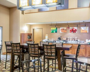 A breakfast area with a buffet setup, including a microwave, waffle maker, and various food items.