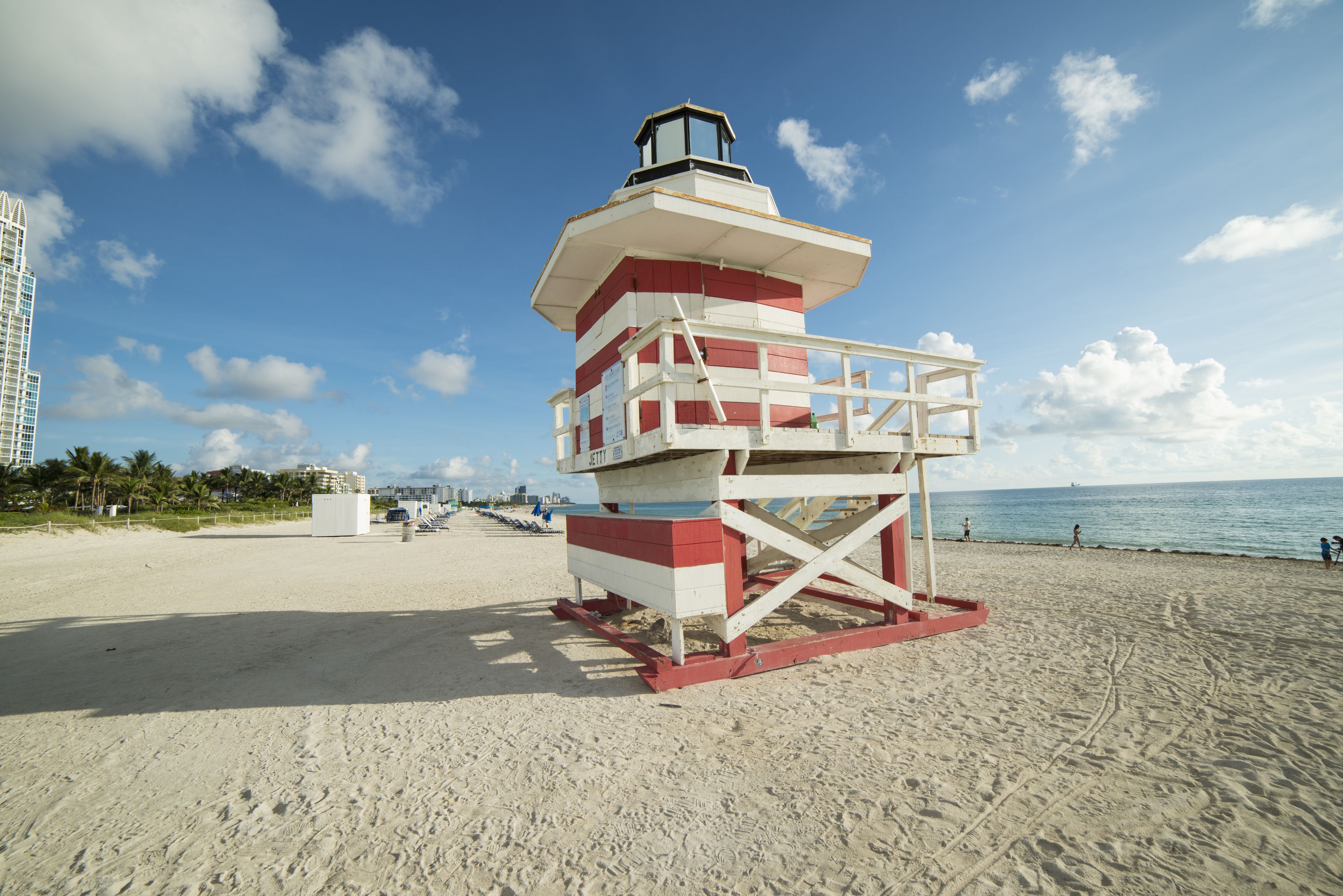 Une tour de surveillance, où se tient un sauveteur, sur une plage de sable, sous un ciel dégagé.