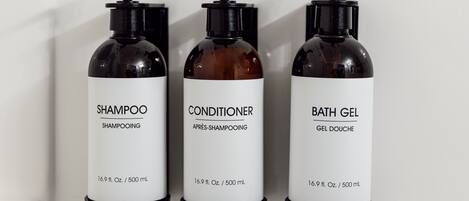 Tres botellas de productos de tocador: champú, acondicionador y gel de baño.