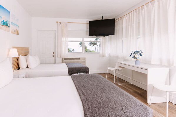 Une chambre d’hôtel avec deux lits, un bureau, une télévision et une fenêtre avec des rideaux.