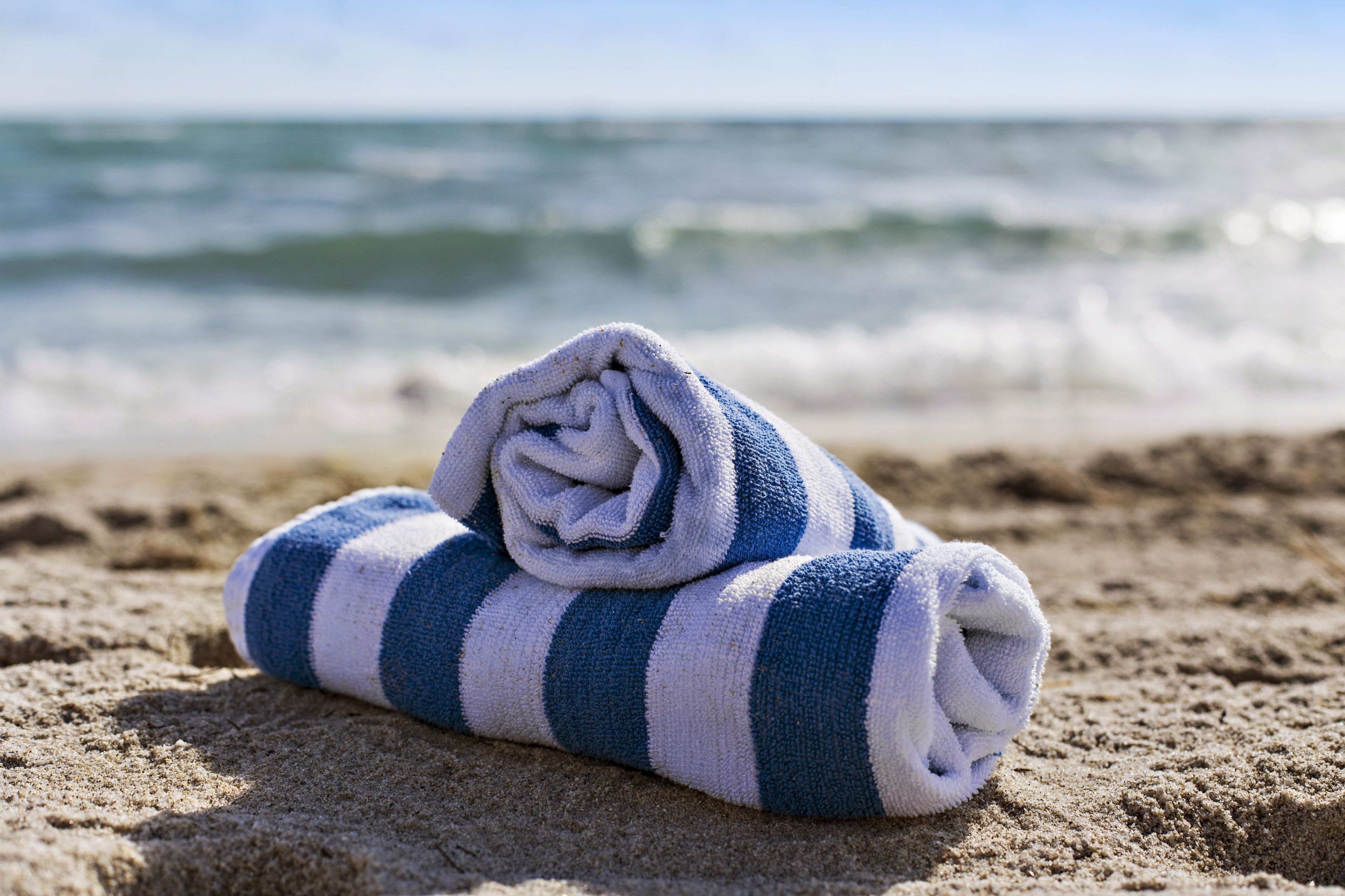 Ein Handtuch auf sandigem Strand, im Hintergrund das Meer.