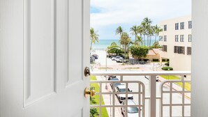 A view from a balcony overlooking a beach with palm trees and a parking lot. - Lorraine Hotel (Miami Beach)