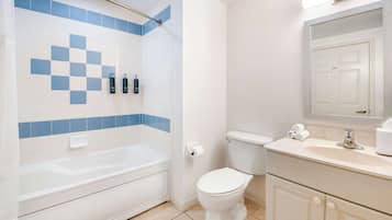 Un baño con bañera, inodoro, lavabo y espejo.