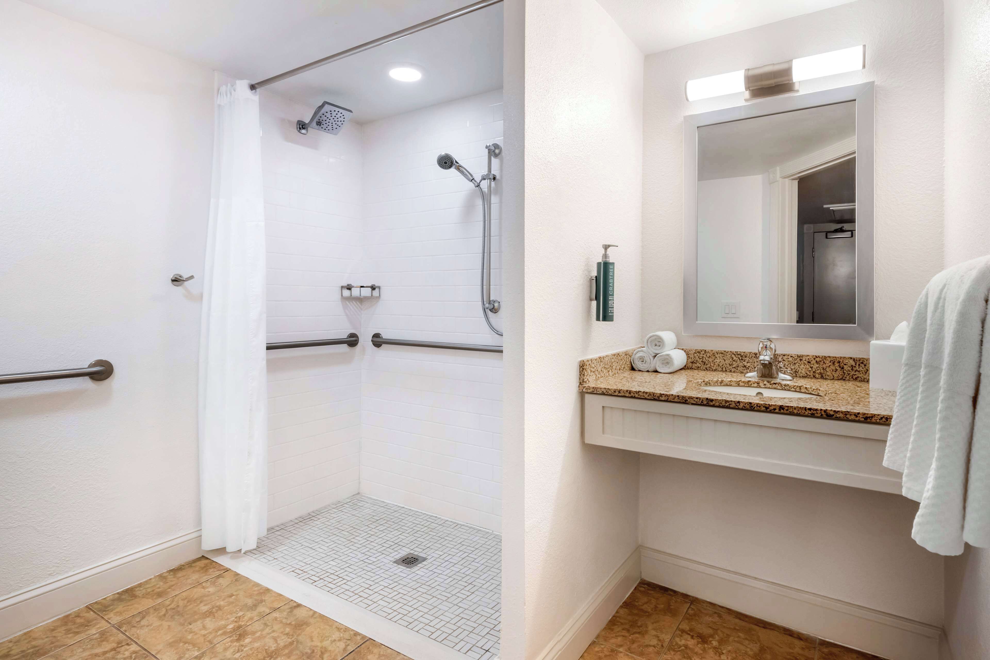 Une salle de bain avec une douche, un lavabo et un miroir.