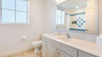 A bathroom with a toilet, a sink, and a mirror.