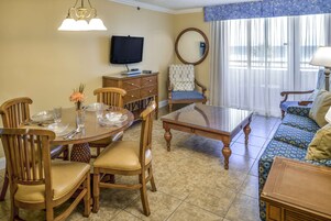 A dining area with a round table, wooden chairs, and a television on the wall.