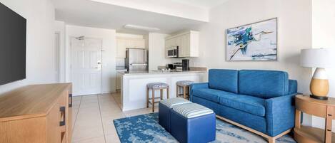 Una sala moderna con un sofá azul, una mesa de centro de madera y una alfombra azul.