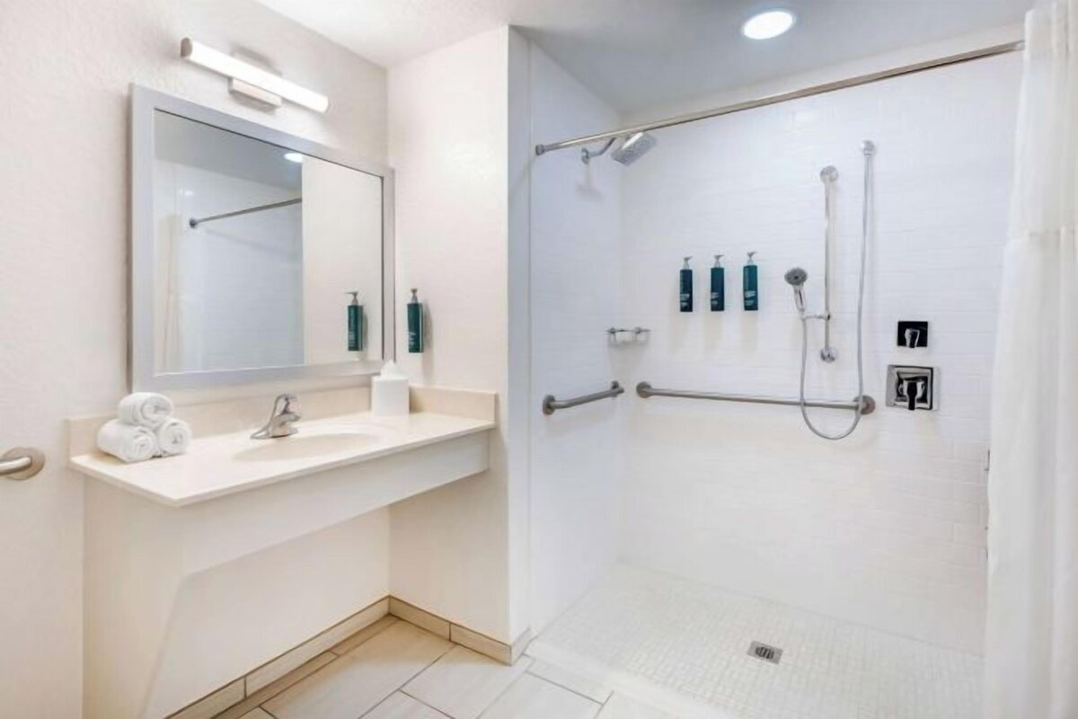 Een moderne badkamer met een witte wastafel, spiegel en douchegedeelte.