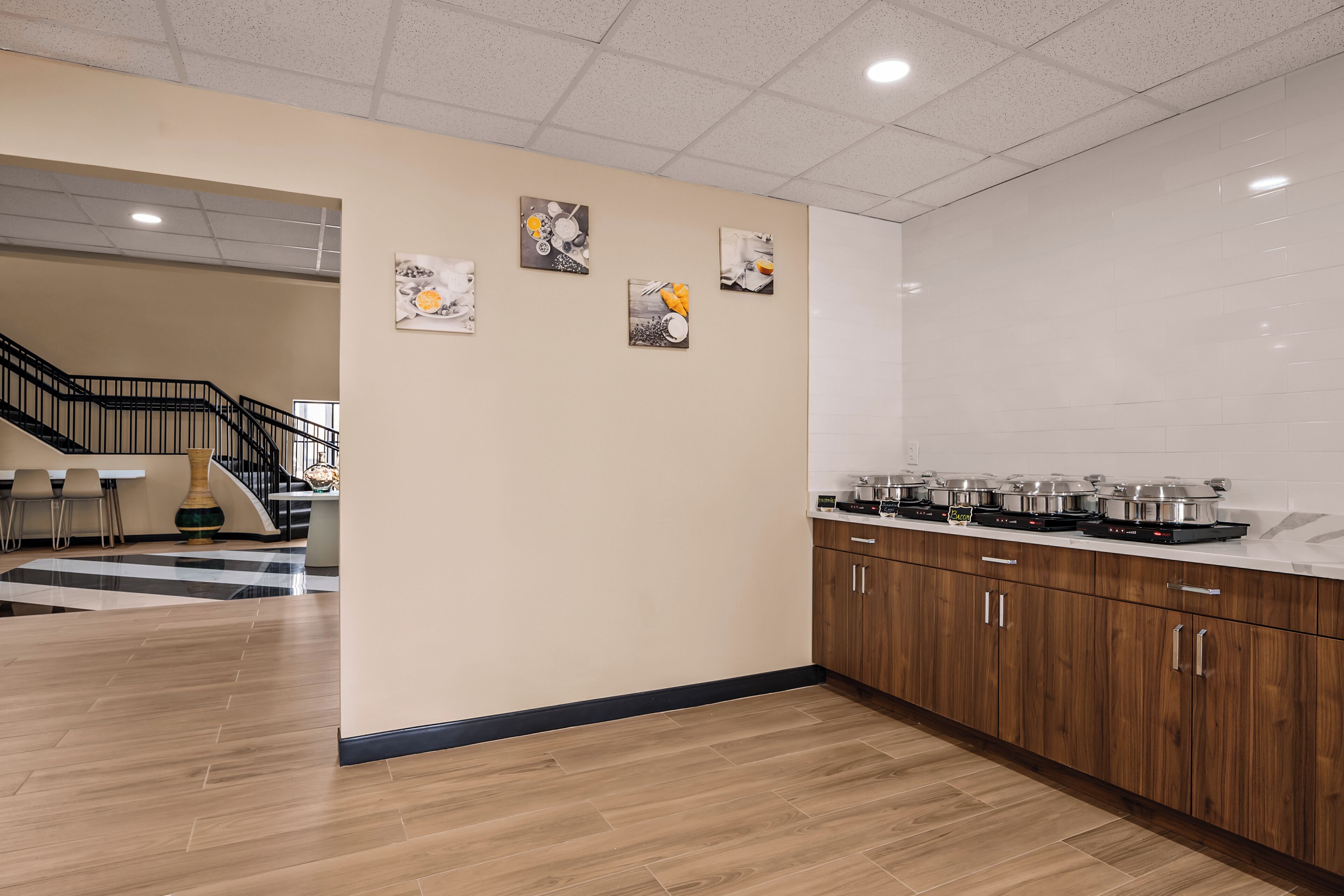 Una cocina moderna con armarios de madera, una encimera con electrodomésticos y una escalera que lleva a otra zona.