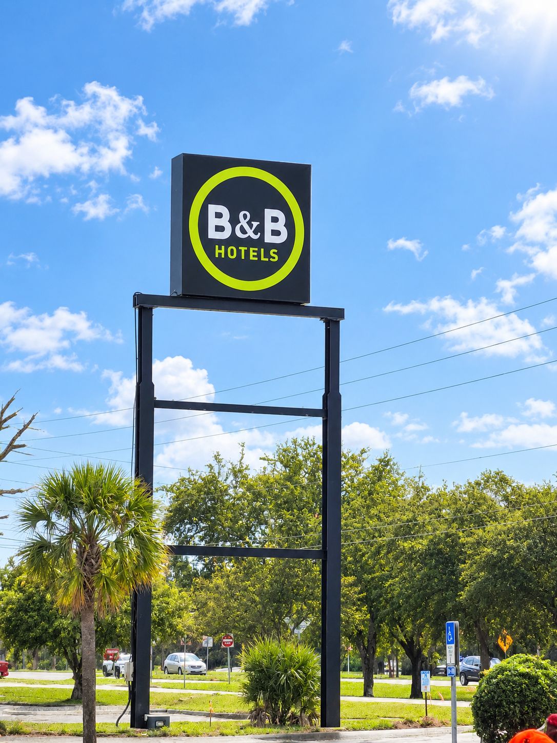 A B&B Hotels sign on a black metal frame with a clear blue sky in the background.