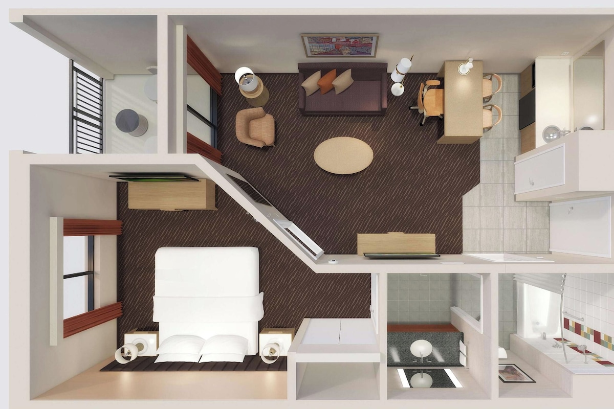 Habitación de hotel con cama, escritorio, silla, mesita, sofá y baño con lavamanos e inodoro.