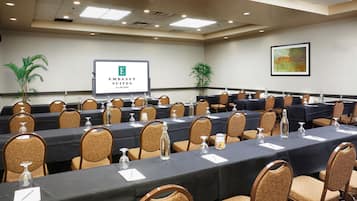 A conference room with long tables, chairs, and a presentation screen.