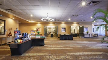 A hotel lobby with a reception desk, a buffet area, and a seating area.