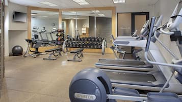 Un gimnasio con cintas de correr, mancuernas y equipo de ejercicio.