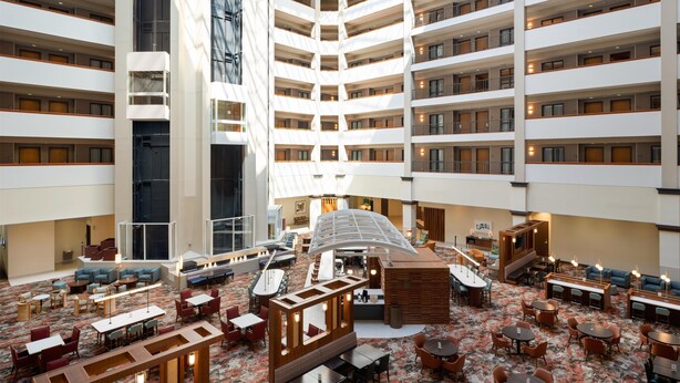 Eine Hotelhalle mit mehreren Etagen, einem zentralen Atrium und verschiedenen Sitzbereichen.