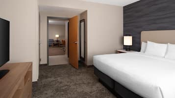 Hotelkamer met een groot bed, een televisie, een houten dressoir en een zichtbare badkamer door een open deur.