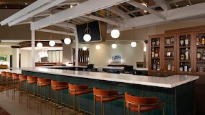 Eine Bar mit einer langen Theke, mehreren Barhocker und einem Getränkeschrank.