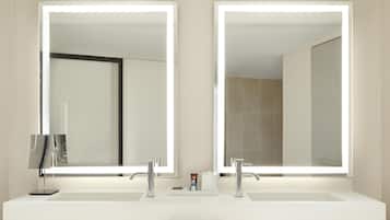 Un baño con lavamanos doble, dos espejos grandes y un mueble de tocador de madera oscura.