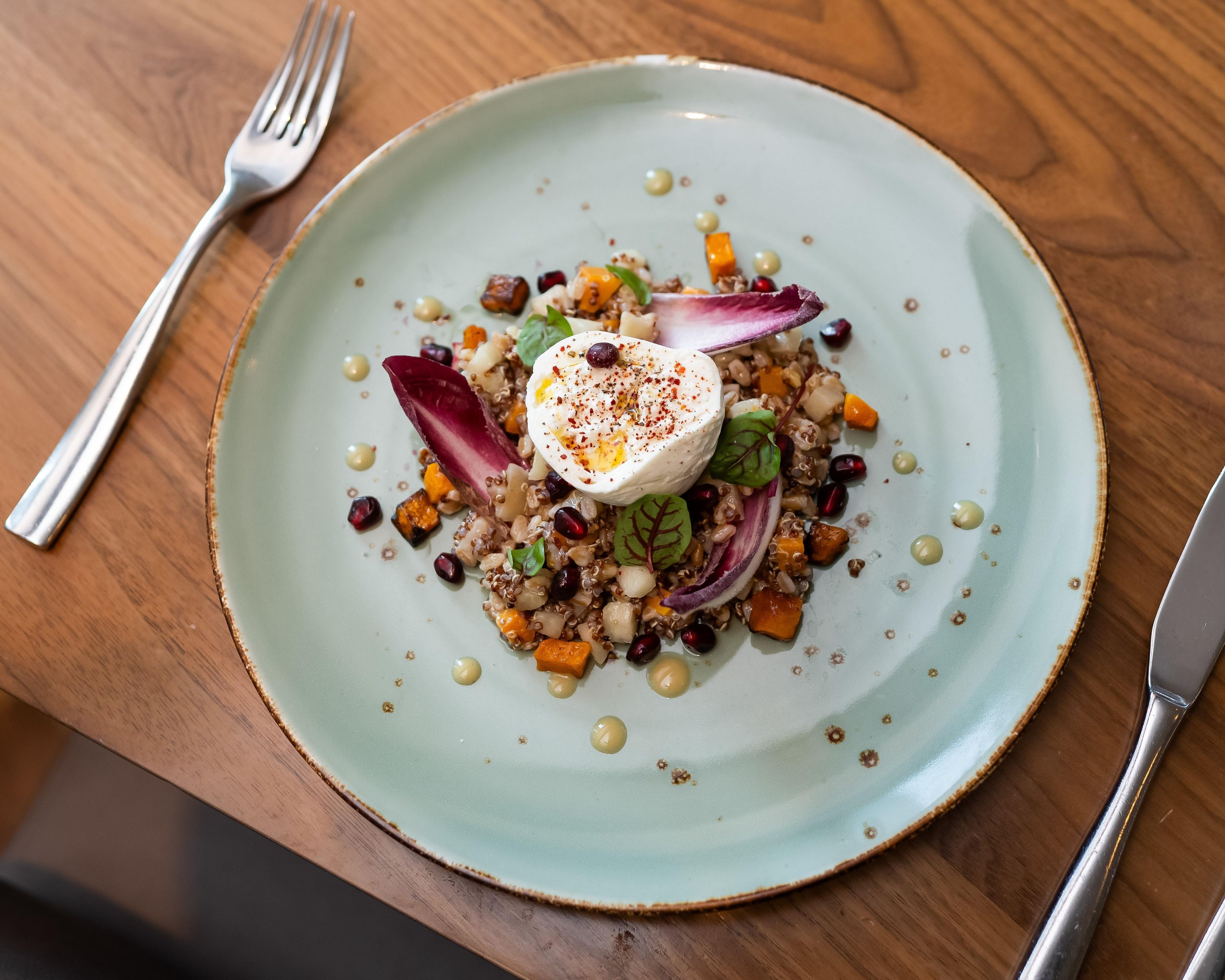 A plate with a variety of food items including grains, vegetables, and a dollop of cream on top.