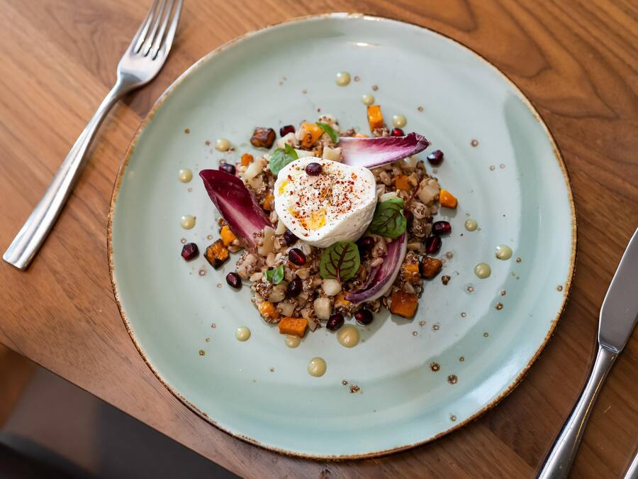 A plate with a variety of food items including grains, vegetables, and a dollop of cream on top.