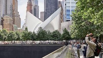 A memorial wall with names inscribed, surrounded by a cityscape with modern buildings.