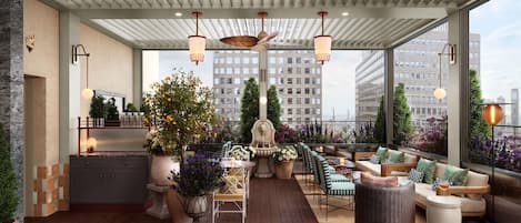 Une terrasse sur le toit, dotée d’une plateforme en bois, d’un espace salon et offrant une vue sur le paysage urbain.
