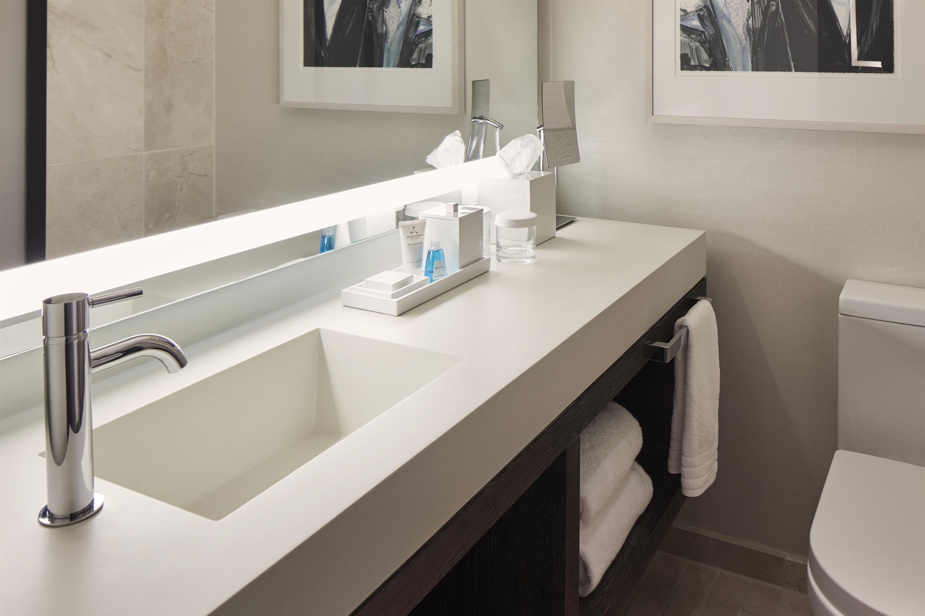 A modern bathroom with a large mirror, a chrome sink, and a toilet.