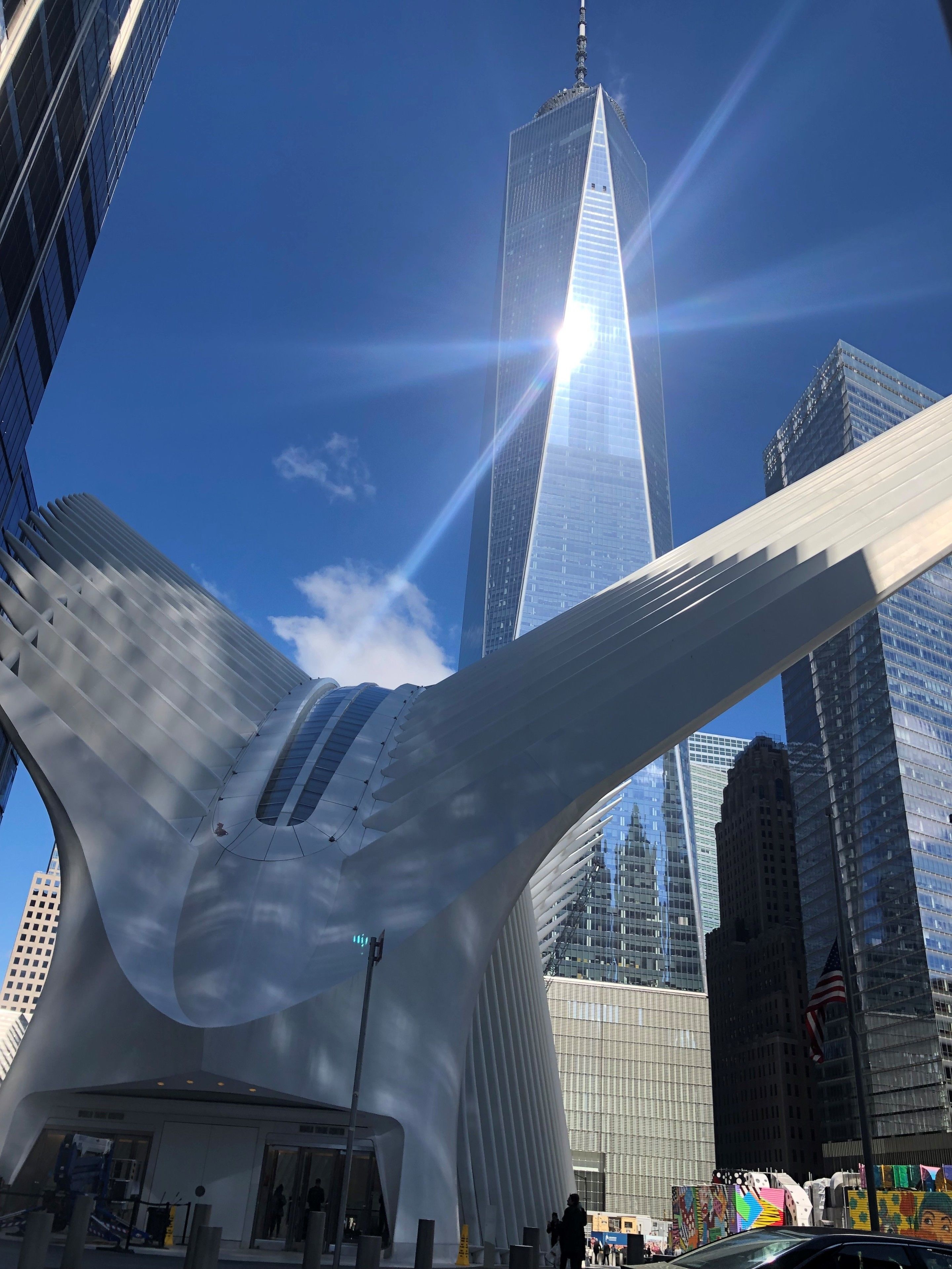 Un edificio moderno con una fachada curva distintiva y una imponente torre de cristal al fondo.