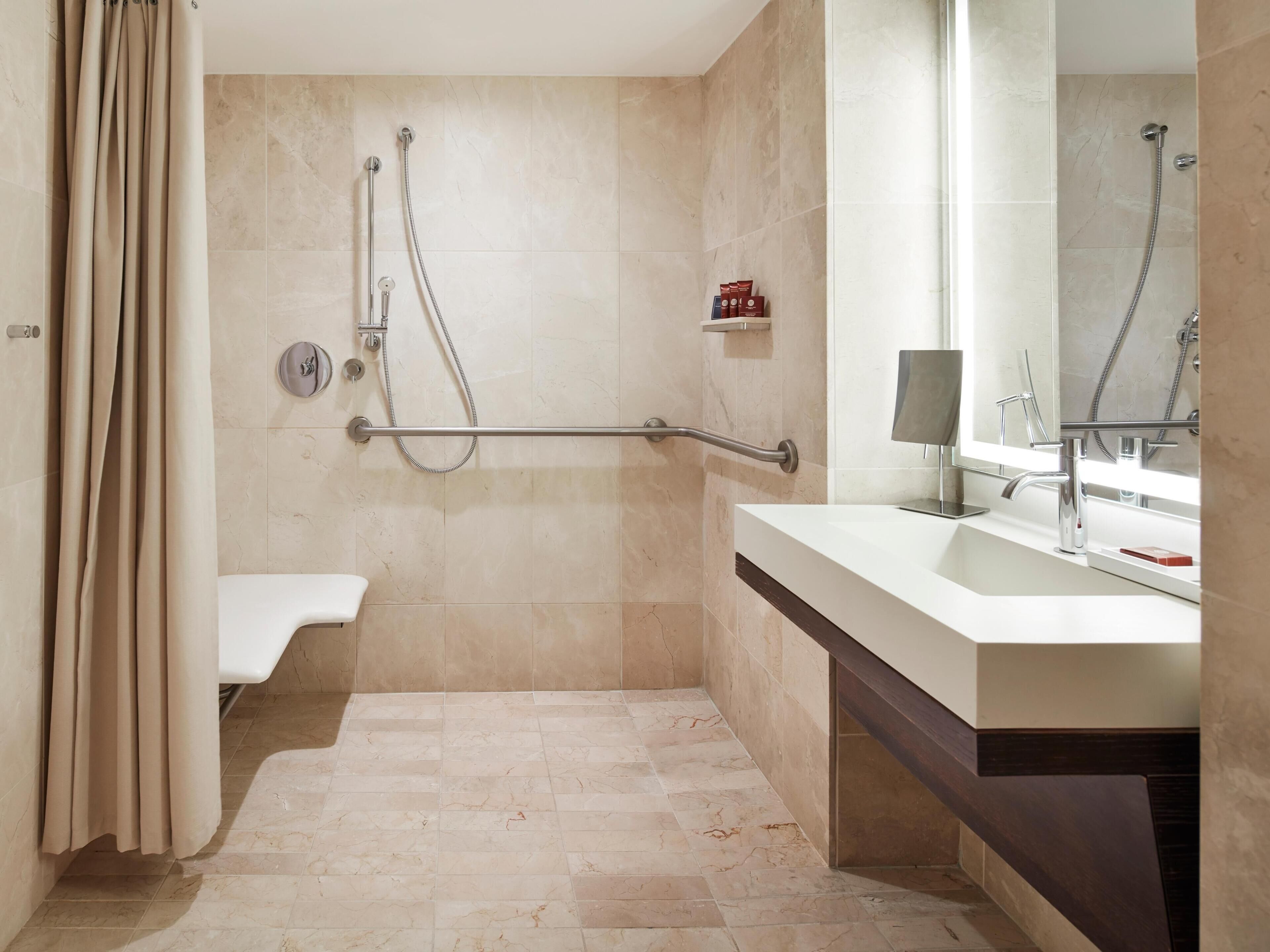 A bathroom with a shower, a toilet, a sink with a mirror, and a towel rack.