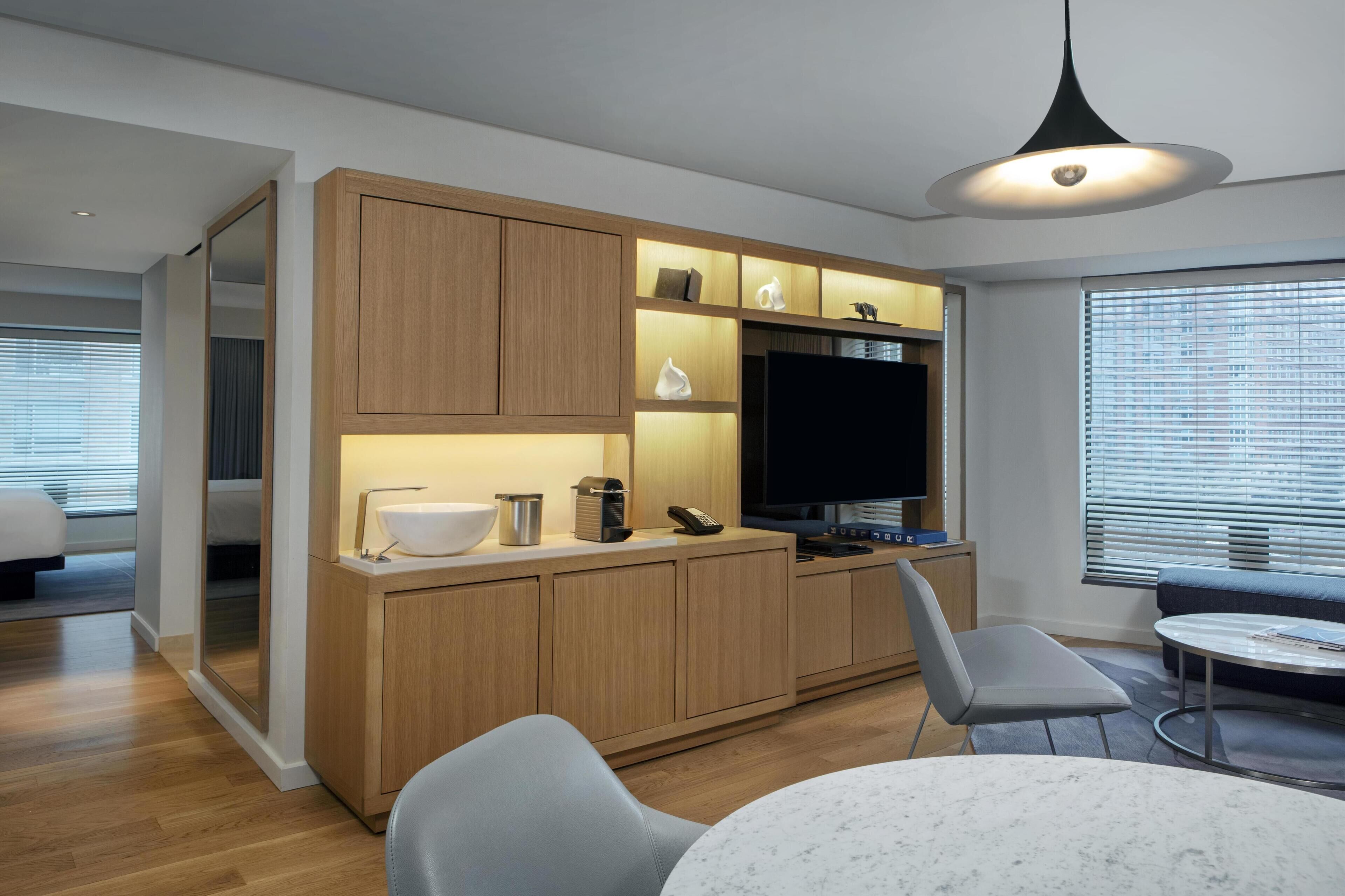 A modern kitchen with wooden cabinets, a built-in TV, and a dining area with a round table and chairs.